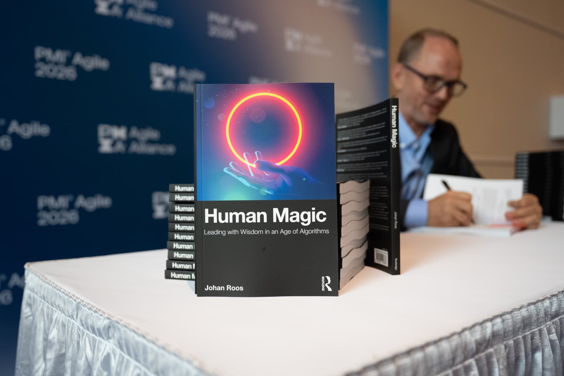 Johan Roos signing copies of Human Magic at a PMI Agile 2026 event.